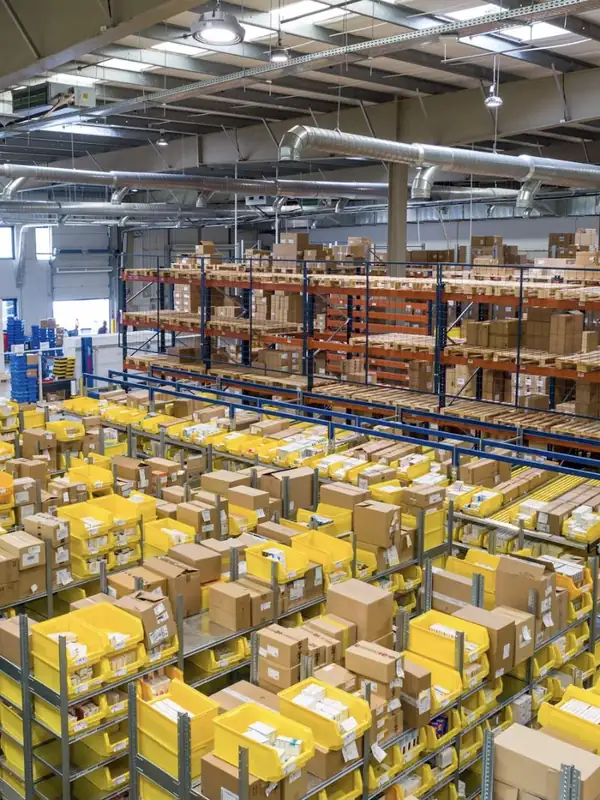 Entrepôt industriel avec rayonnages, cartons et bacs de préparation